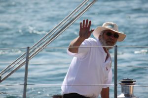 Guild member waving from deck of wooden yacht